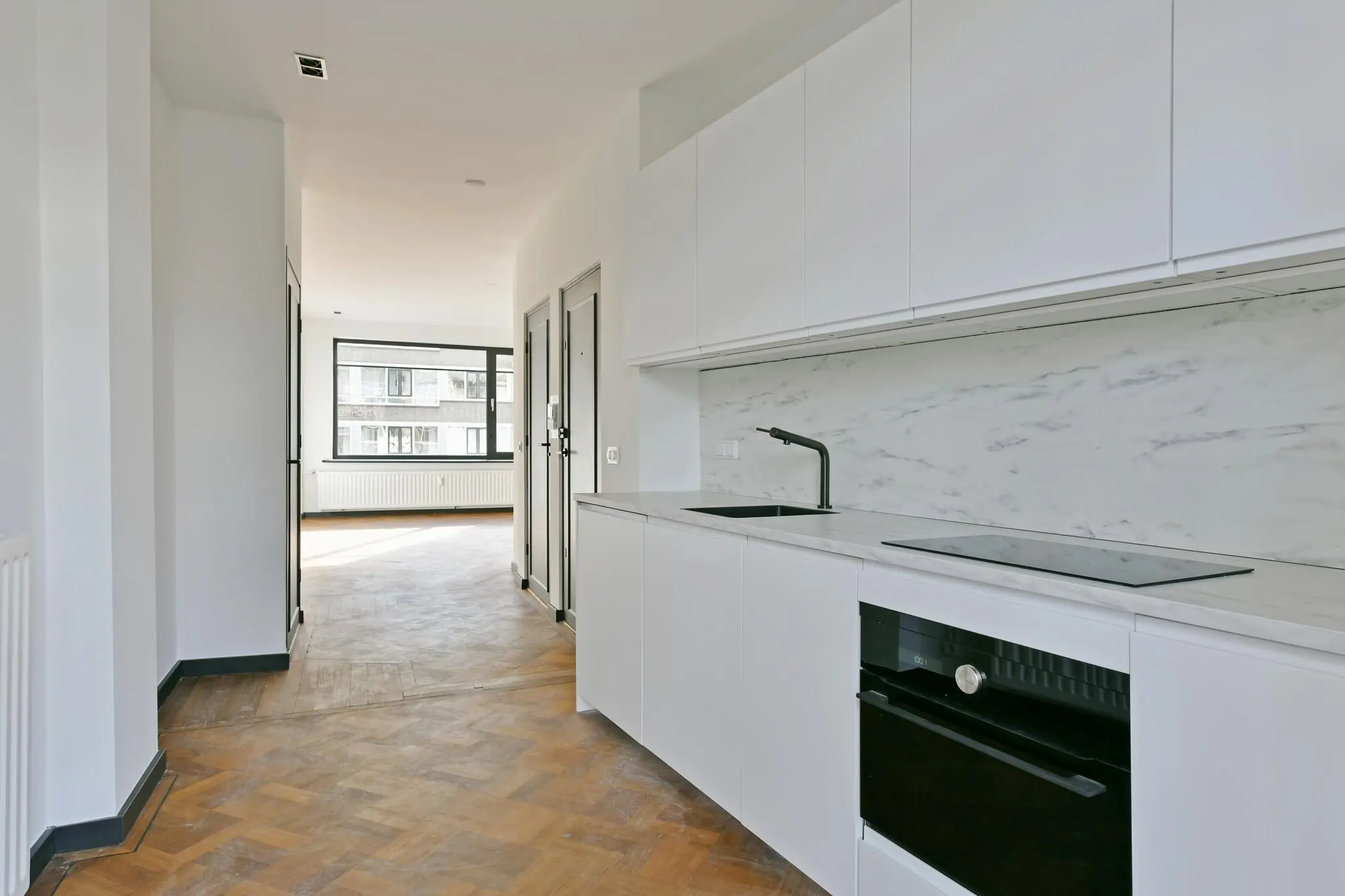 Moderne witte keuken met marmeren achterwand in een appartement aan de Cornelis Dopperkade.